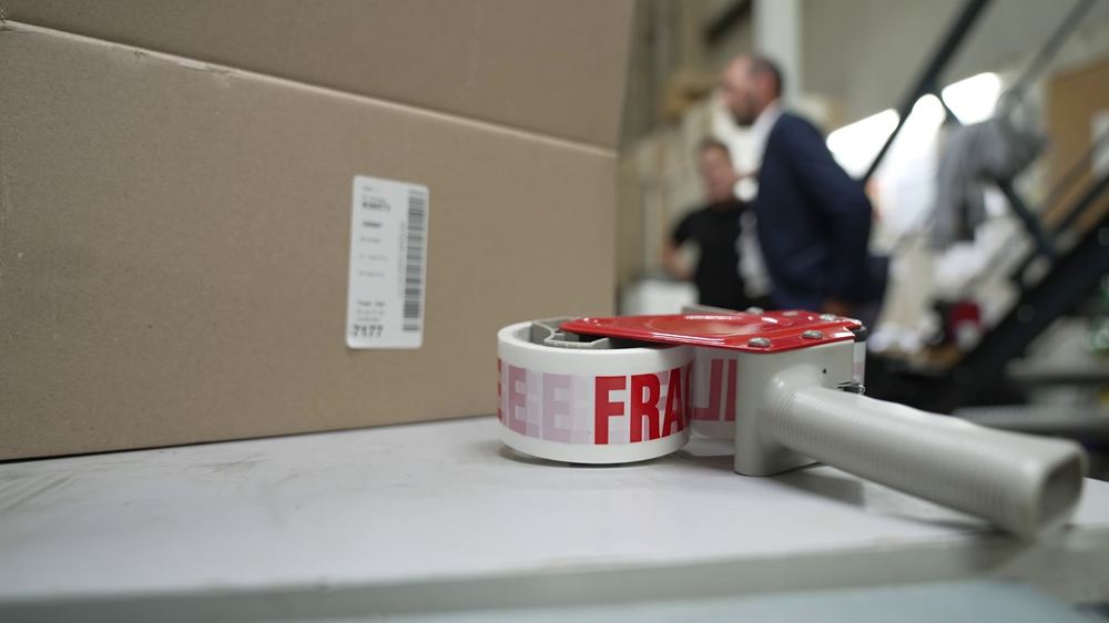 Carton et dérouleur de ruban Fragile au poste d'expédition