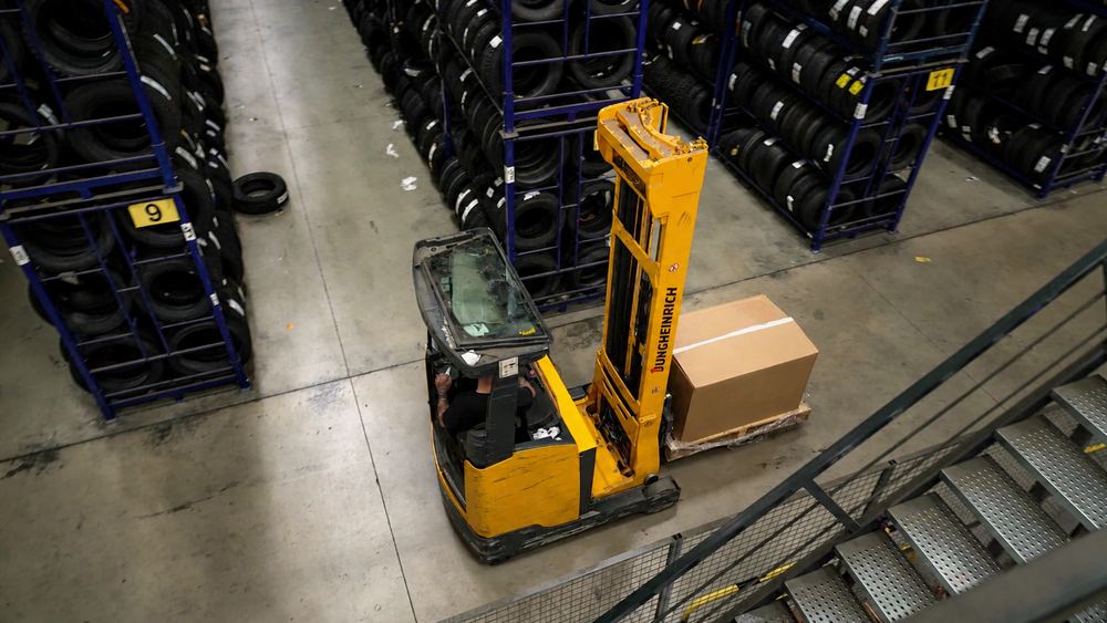 Chariot élévateur transportant un carton dans l'entrepôt de pneus