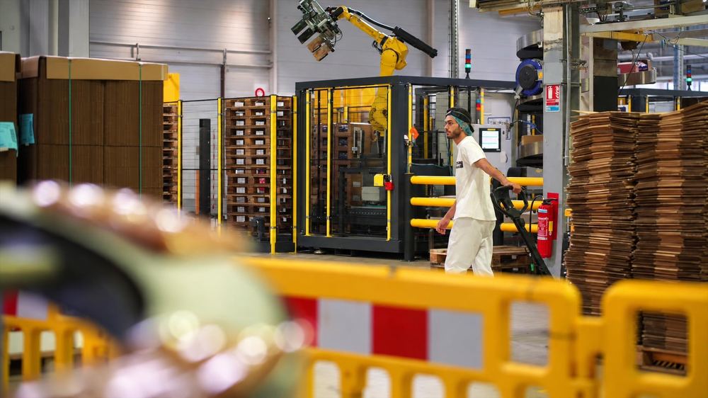 Opérateur sur une ligne de production, piles de cartons à plat
